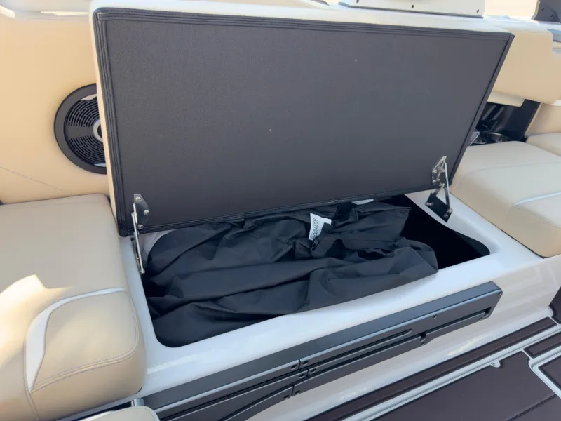 Slide: The Image of 2025 Supra SL 550 boat storage compartment with open lid and black cover inside. - 24