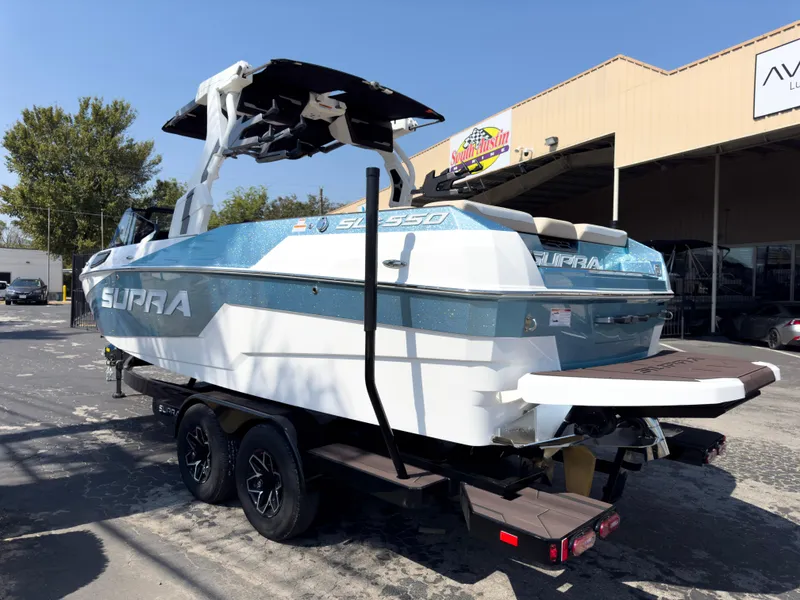Slide: The Image of 2025 Supra SL 550 boat on trailer, parked outdoors near a building. - 7
