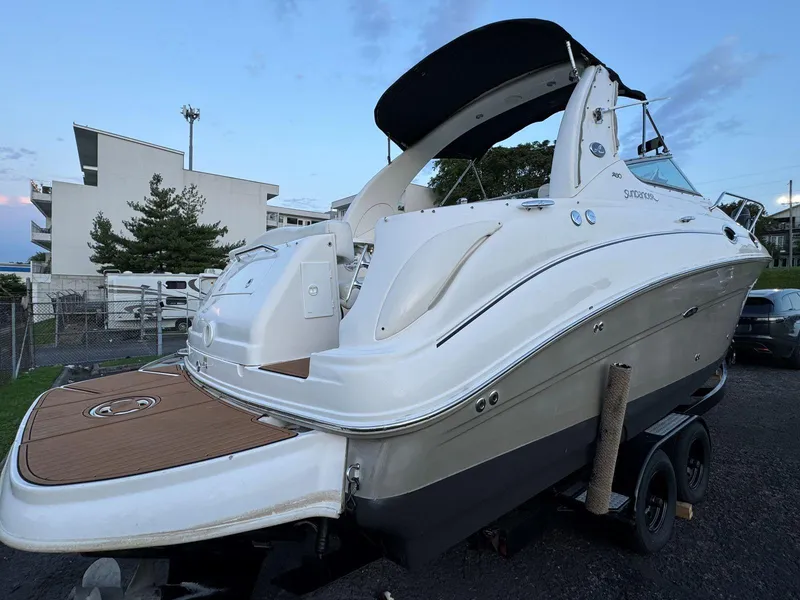 Slide: The Image of 2006 Sea Ray 280 Sundancer boat on trailer, white exterior, docked outdoors. - 11