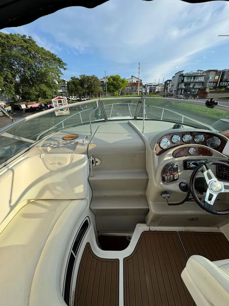 Slide: The Image of 2006 Sea Ray 280 Sundancer cockpit with steering wheel and gauges, docked near waterfront homes. - 14