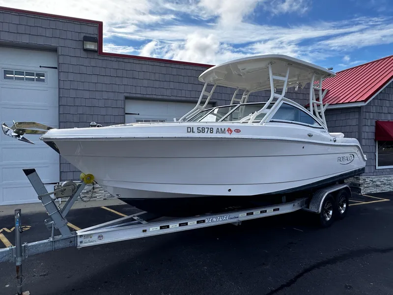 Slide: The Image of 2019 Robalo R247 Dual Console boat on trailer, parked outside a building. - 0