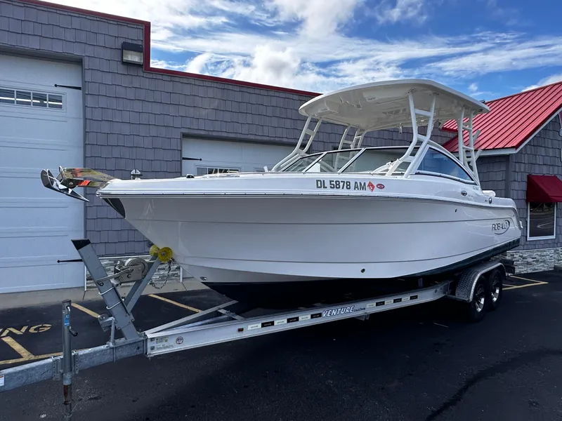 Slide: The Image of 2019 Robalo R247 Dual Console boat on trailer, parked outside building. - 1