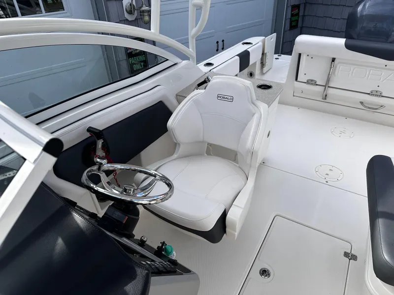 Slide: The Image of 2019 Robalo R247 Dual Console boat interior with white seating and steering wheel. - 18