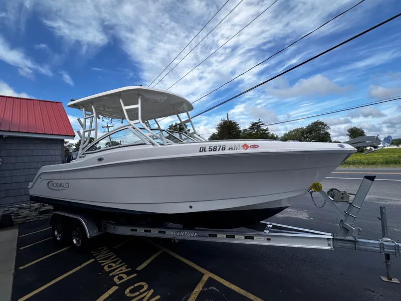 Slide: The Image of 2019 Robalo R247 Dual Console boat on trailer, parked outdoors under cloudy sky. - 7