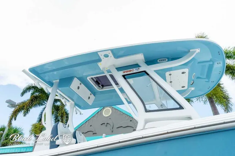 Slide: The Image of 2025 Sea Fox 288 Commander Center Console boat with blue T-top and palm trees. - 2