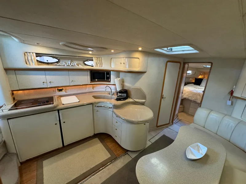 Slide: The Image of Interior of a 1997 Sea Ray 450 Sundancer yacht, featuring a modern kitchen and cozy seating area. - 16