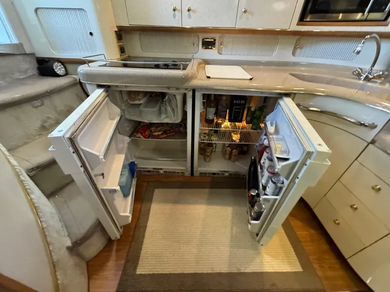 Slide: The Image of Kitchen area of a 1997 Sea Ray 450 Sundancer yacht with open fridge and cabinets. - 25
