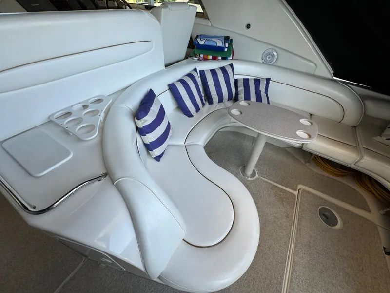 Slide: The Image of 1997 Sea Ray 450 Sundancer interior with white seating, striped cushions, and a small table. - 31