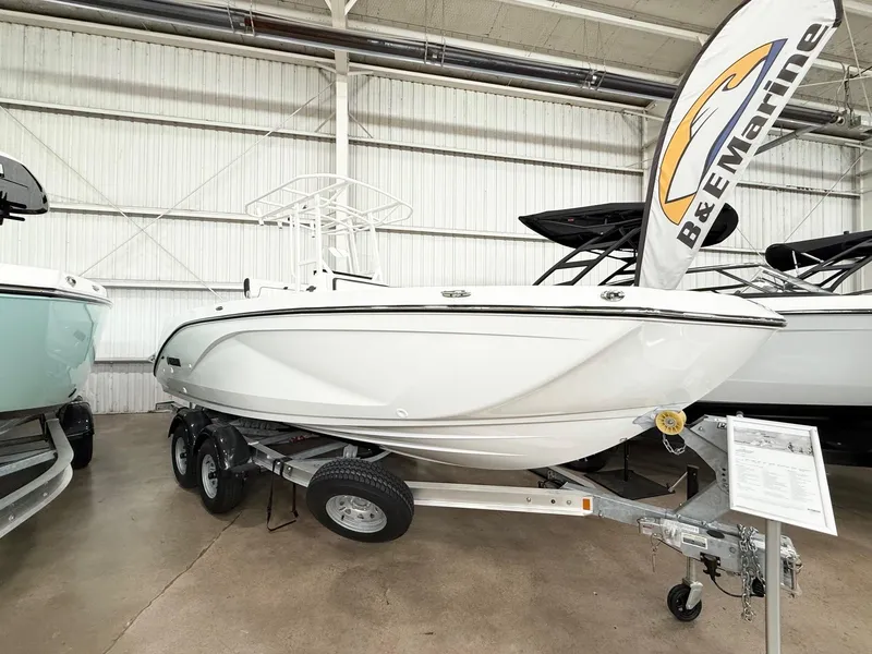 Slide: The Image of 2025 Yamaha Boats 220 FSH Sport displayed indoors on a trailer. - 2