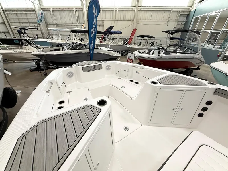 Slide: The Image of 2025 Yamaha Boats 220 FSH Sport interior, showcasing spacious seating and sleek design in a showroom. - 8