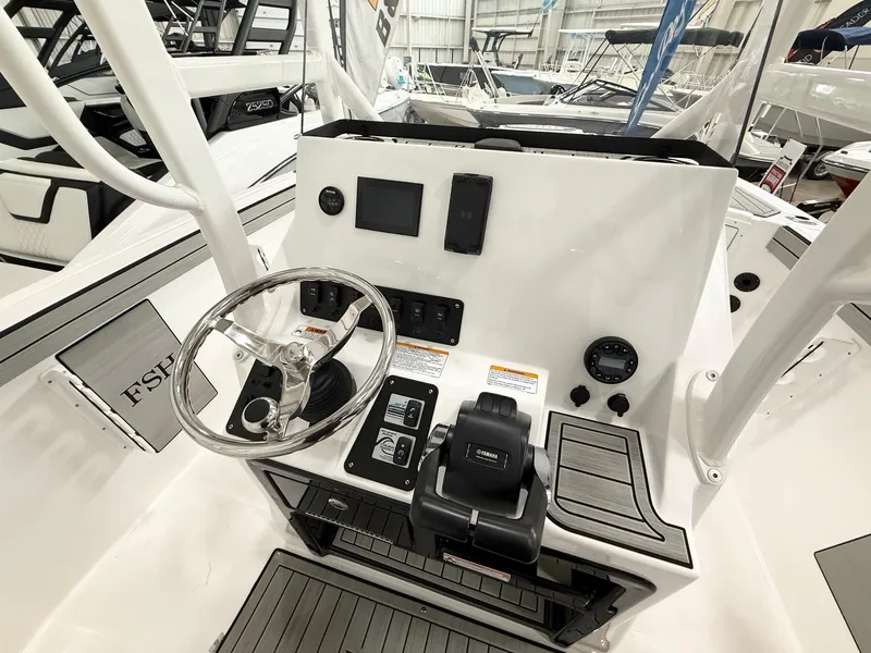 Slide: The Image of 2025 Yamaha Boats 220 FSH Sport dashboard with steering wheel and controls in a showroom. - 9