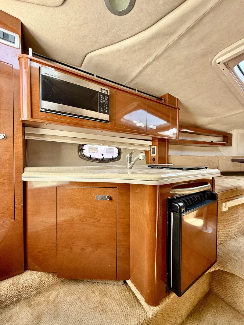Slide: The Image of 2010 Sea Ray 280 Sundancer cabin with kitchenette, microwave, and compact fridge. - 10