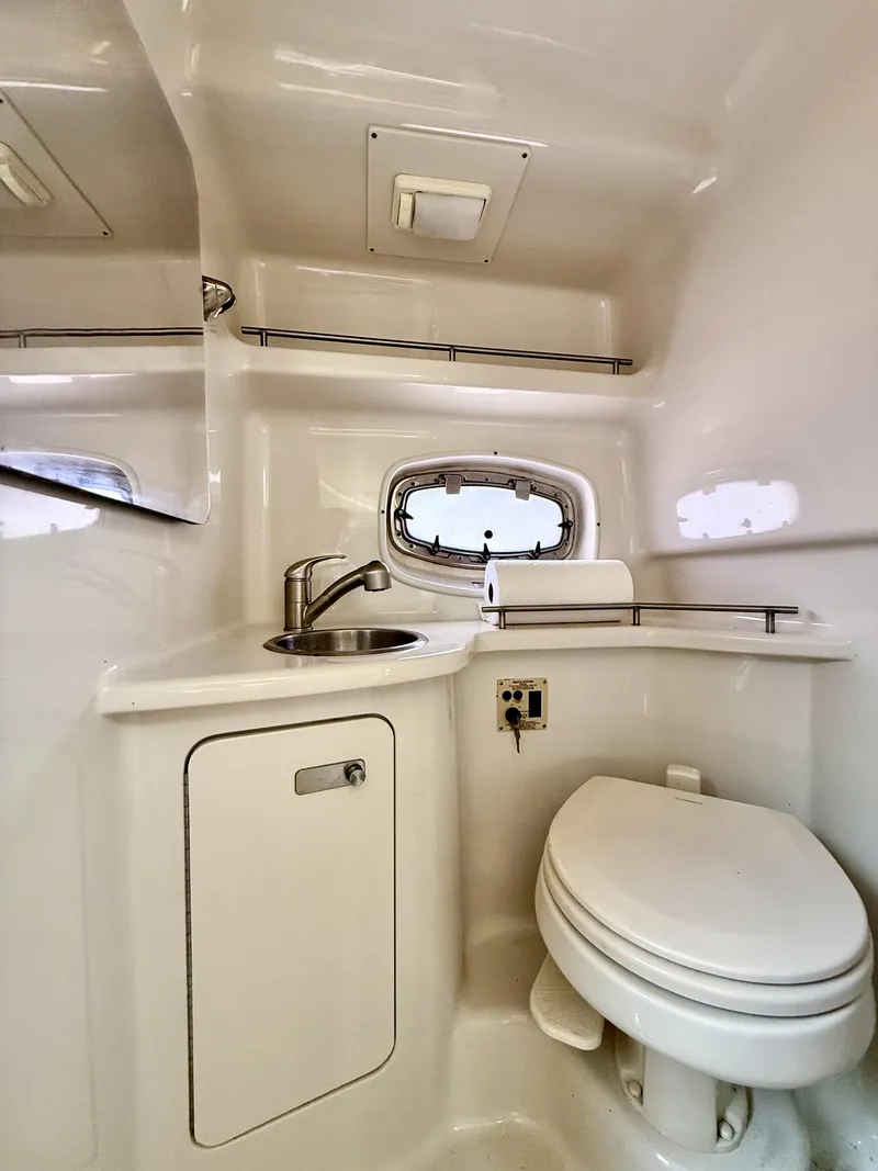 Slide: The Image of 2010 Sea Ray 280 Sundancer bathroom with sink, toilet, and porthole window. - 11