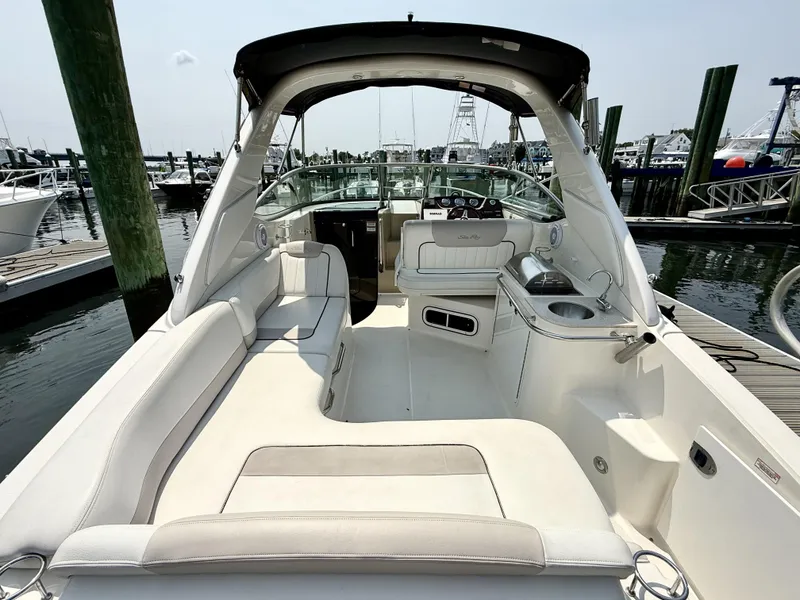 Slide: The Image of 2010 Sea Ray 280 Sundancer boat interior with white seating, docked at marina. - 3