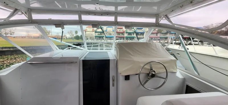 Slide: The Image of 1995 Cabo 35 Express boat interior with covered steering wheel, docked near colorful buildings. - 11