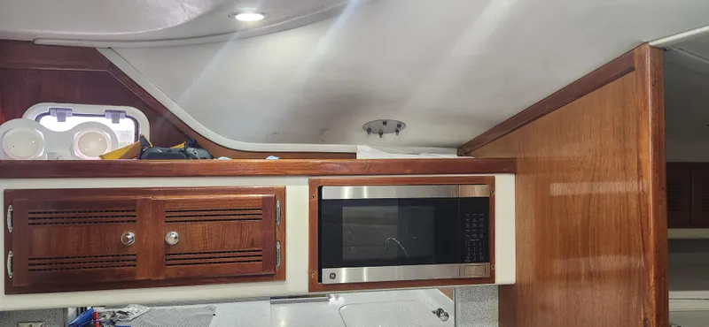 Slide: The Image of Interior of a 1995 Cabo 35 Express boat with wooden cabinets and a microwave. - 26