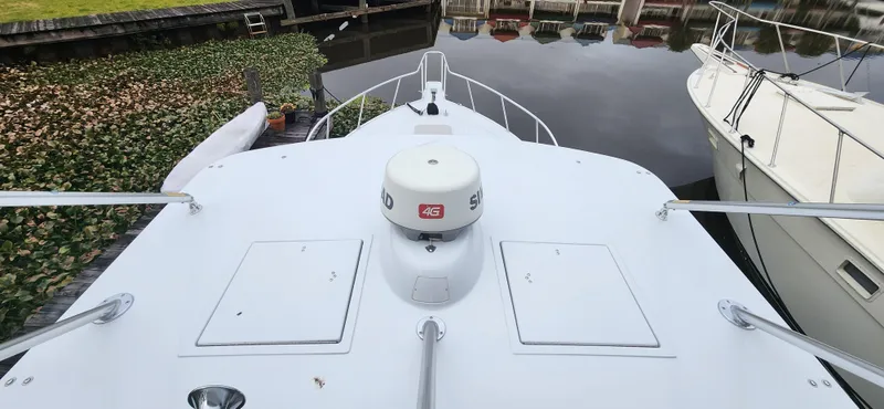 Slide: The Image of Bow view of a 1995 Cabo 35 Express boat docked near water plants. - 46