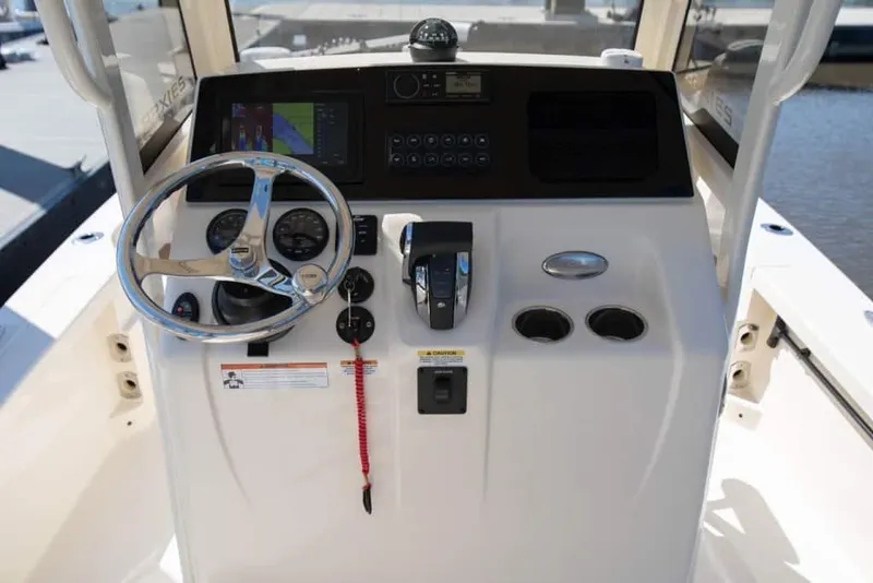 Slide: The Image of 2026 Scout 231 XSB boat dashboard with steering wheel and navigation controls. - 2