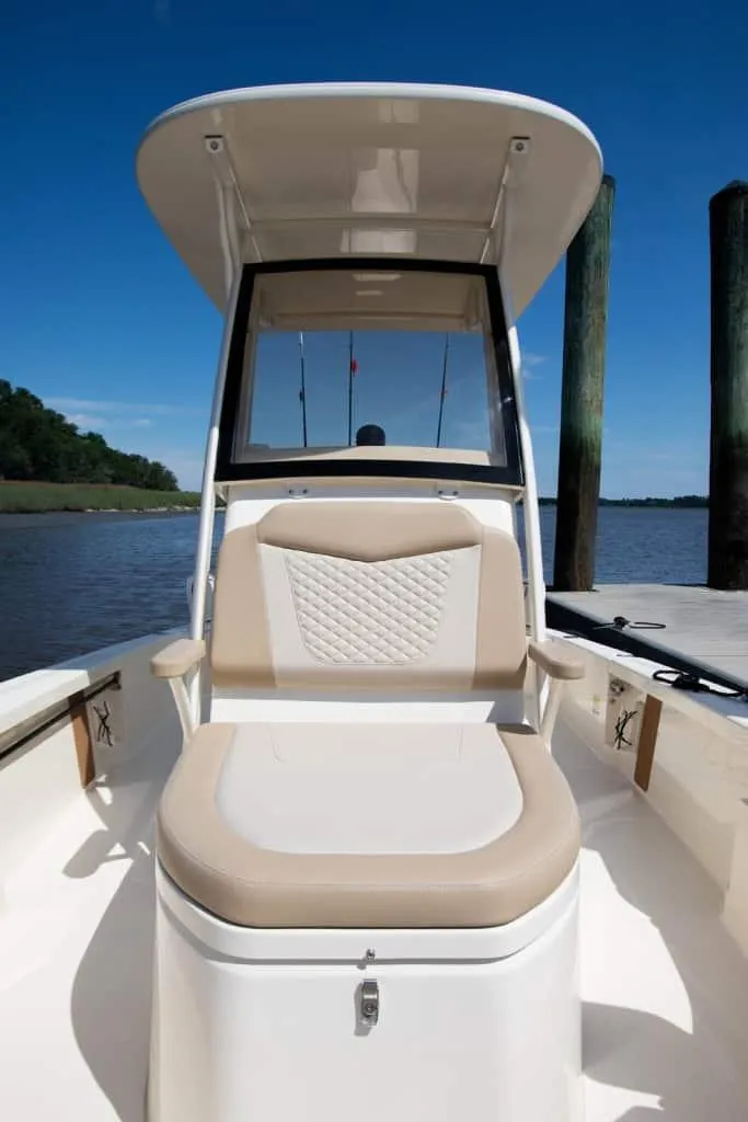 Slide: The Image of 2026 Scout 231 XSB boat with cushioned seating, docked by wooden posts under clear blue sky. - 3