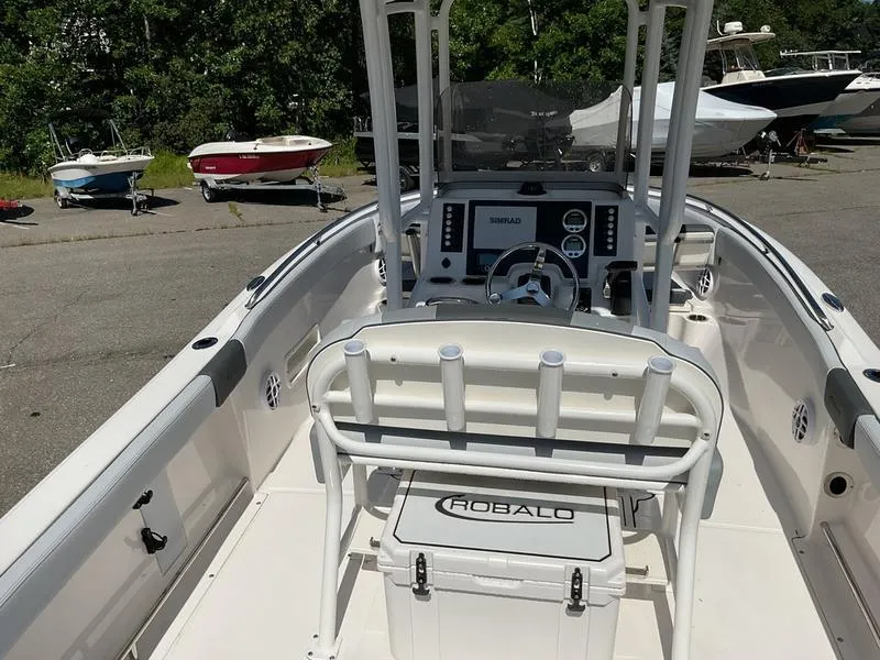 Slide: The Image of 2025 Robalo 222 EX boat interior with steering console and seating, docked outdoors. - 12