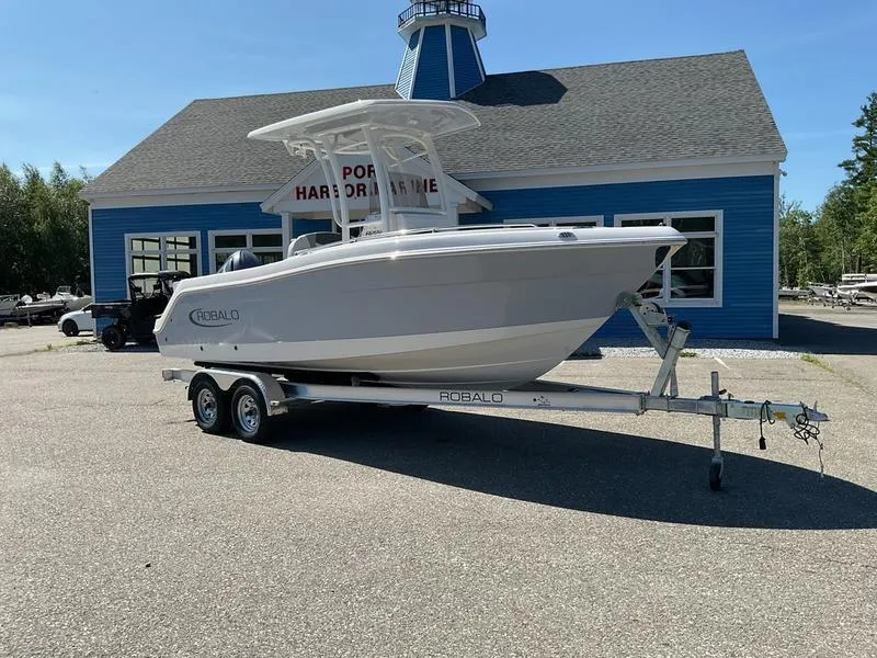 Slide: The Image of 2025 Robalo 222 EX boat on trailer outside blue building. - 7