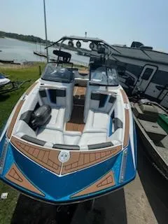 Slide: The Image of 2017 Nautique Super Air Nautique G23 boat with blue and white design, docked by a lake. - 2