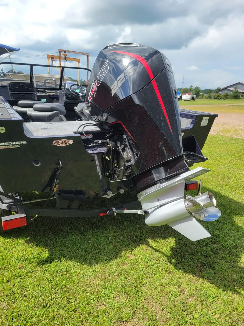 Slide: The Image of 2025 Tracker Targa V-19 WT boat with powerful outboard motor on grassy field. - 2