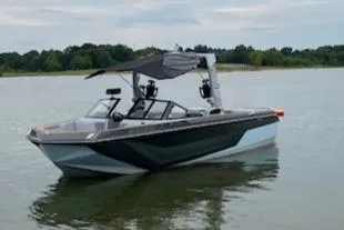 Slide: The Image of 2024 Nautique GS24 boat on a calm lake with trees in the background. - 0