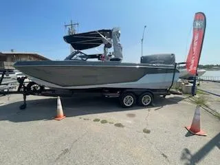 Slide: The Image of 2024 Nautique GS24 boat on trailer, outdoor display with banner and traffic cones. - 10