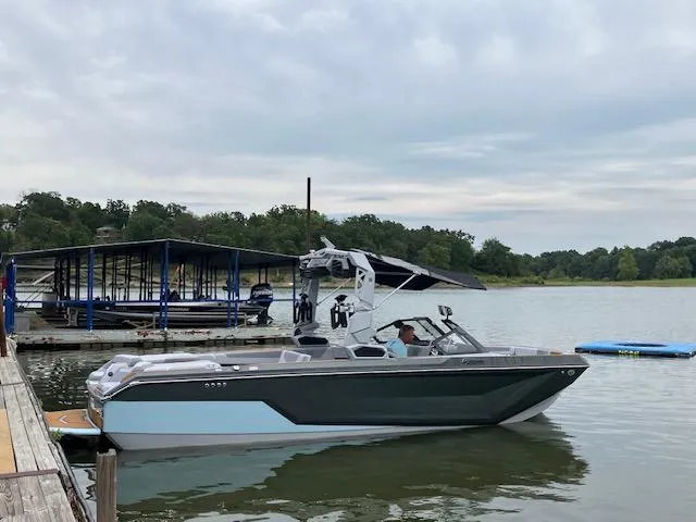 Slide: The Image of 2024 Nautique GS24 boat docked on a serene lake with overcast skies. - 4
