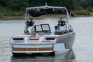 Slide: The Image of 2024 Nautique GS24 boat on a calm lake with lush greenery. - 5