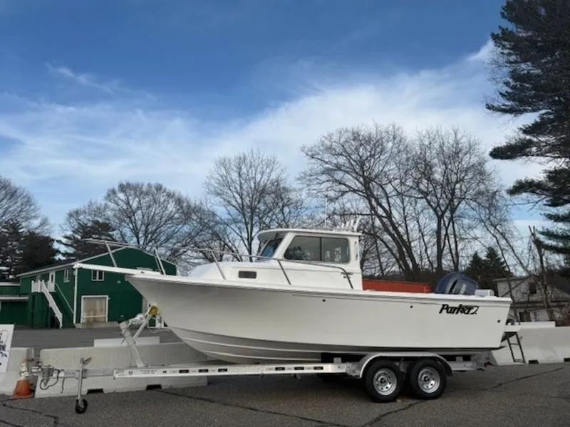 Slide: The Image of 2025 Parker 2120 Sport Cabin boat on trailer, parked outdoors under a clear sky. - 1