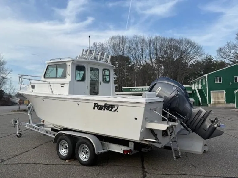 Slide: The Image of 2025 Parker 2120 Sport Cabin boat on trailer, parked outdoors under a cloudy sky. - 3
