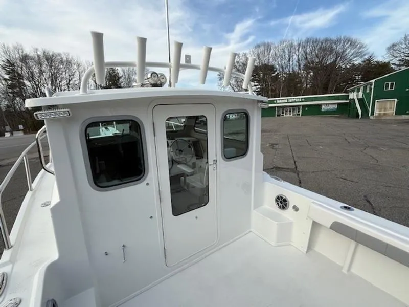 Slide: The Image of 2025 Parker 2120 Sport Cabin boat, docked, with white cabin and clear windows. - 6