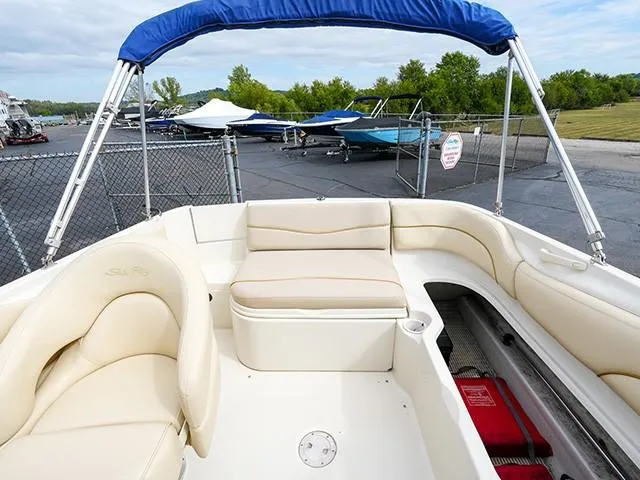 Slide: The Image of 2001 Sea Ray 190 Sundeck boat with beige seating and blue canopy in a marina. - 6