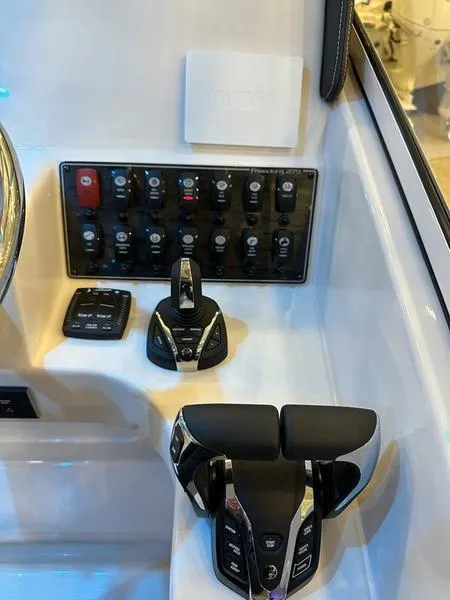 Slide: The Image of Control panel of 2025 Grady-White Freedom 275 boat with switches and throttle controls. - 10