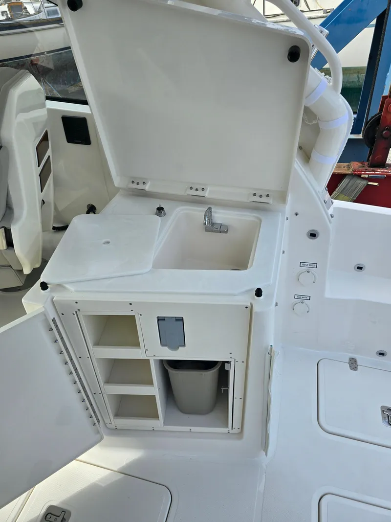 Slide: The Image of 2025 Pursuit DC 306 Dual Console boat interior with sink and storage compartments. - 10