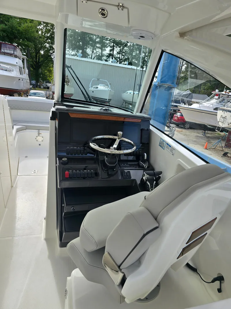 Slide: The Image of 2025 Pursuit DC 306 Dual Console boat interior with steering wheel and control panel. - 12