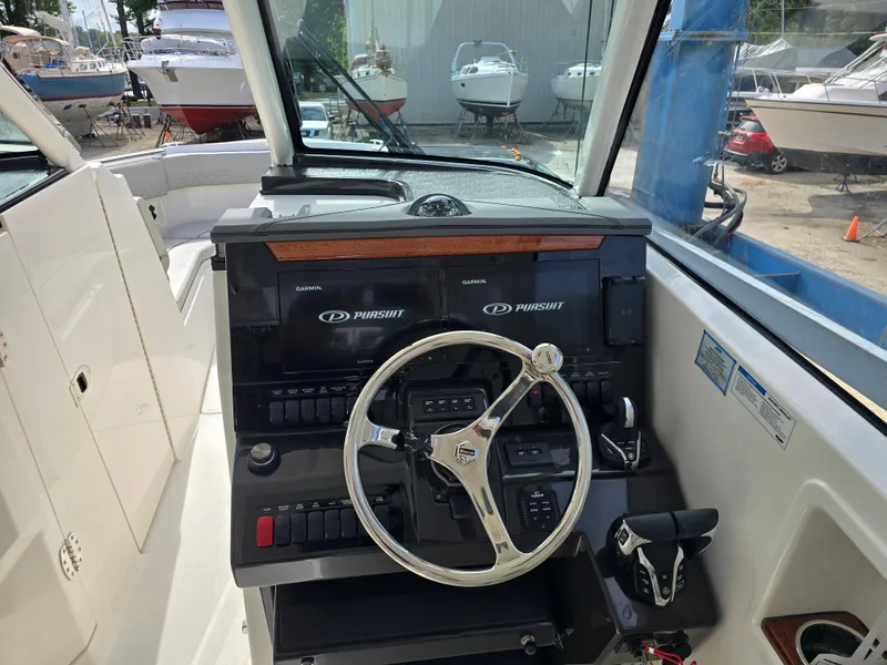 Slide: The Image of 2025 Pursuit DC 306 Dual Console boat dashboard with steering wheel and controls. - 13