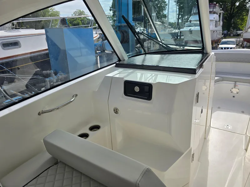Slide: The Image of 2025 Pursuit DC 306 Dual Console interior with seating and storage, docked near other boats. - 15