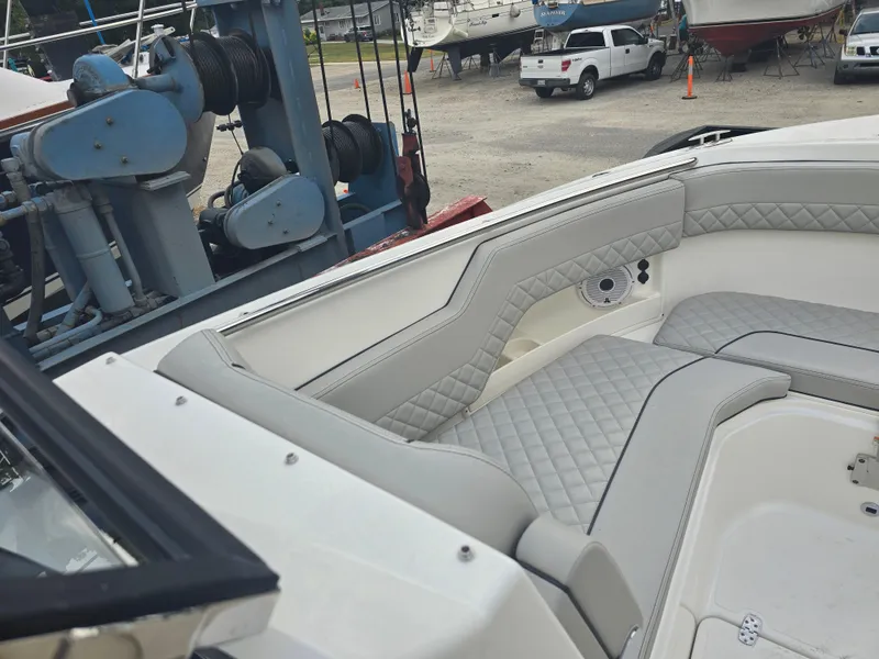 Slide: The Image of 2025 Pursuit DC 306 Dual Console boat interior with quilted seating, docked near marine equipment. - 22