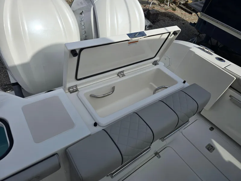 Slide: The Image of 2025 Pursuit DC 306 Dual Console boat with open storage compartment and cushioned seating. - 4