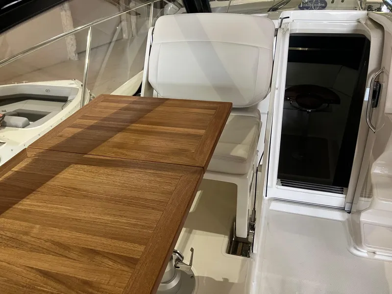 Slide: The Image of 2025 Boston Whaler 325 Conquest interior with wooden table and white seating. - 12