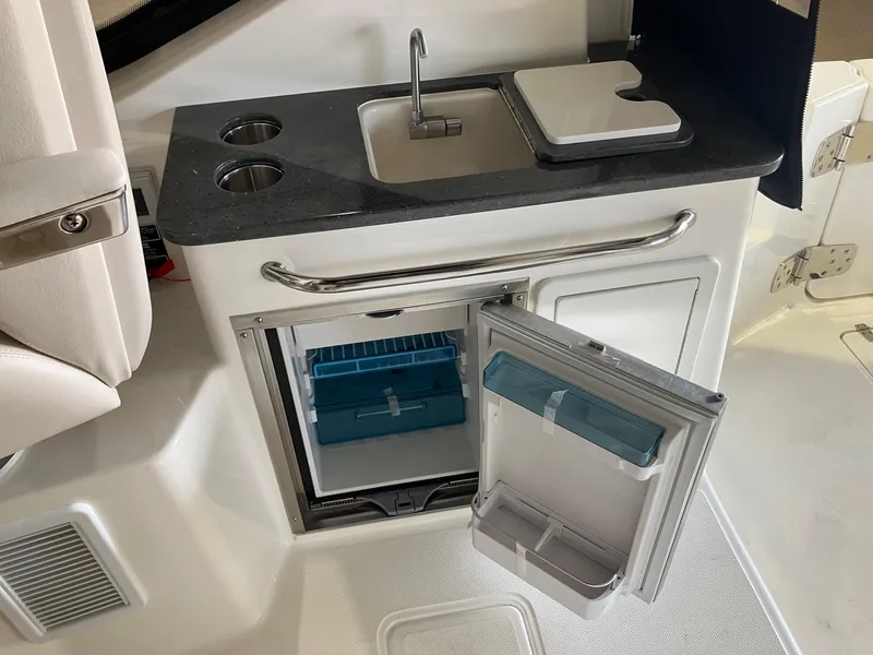 Slide: The Image of 2025 Boston Whaler 325 Conquest kitchenette with sink, storage, and mini fridge. - 14
