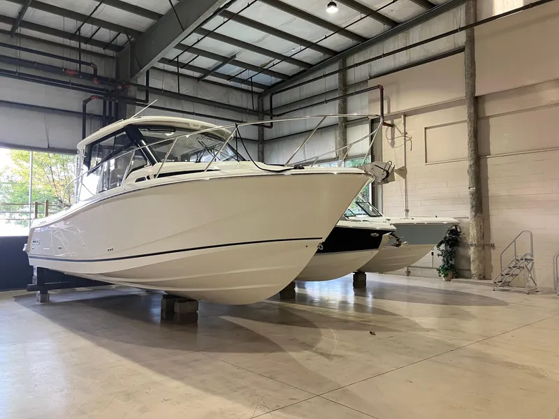 Slide: The Image of 2025 Boston Whaler 325 Conquest boat displayed in a spacious indoor showroom. - 2