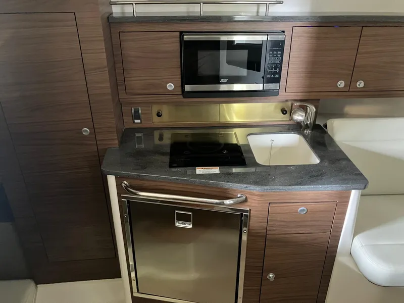 Slide: The Image of 2025 Boston Whaler 325 Conquest galley with microwave, sink, and stainless steel appliances. - 21