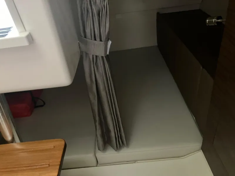 Slide: The Image of 2025 Boston Whaler 325 Conquest cabin interior with cushioned seating and privacy curtain. - 22