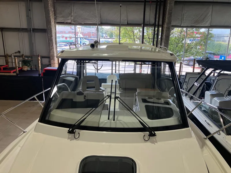Slide: The Image of 2025 Boston Whaler 325 Conquest boat in showroom, front view with windshield and seating. - 25