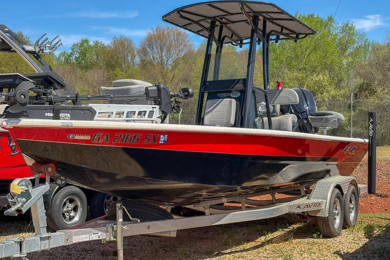 Slide: The Image of 2022 Avid 23 Mag boat on trailer, red and black design, parked outdoors. - 8