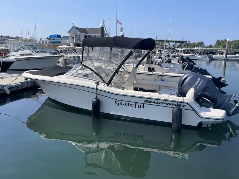 Slide: The Image of 2020 Grady-White 215 Freedom boat docked in marina, featuring black canopy and outboard motor. - 7